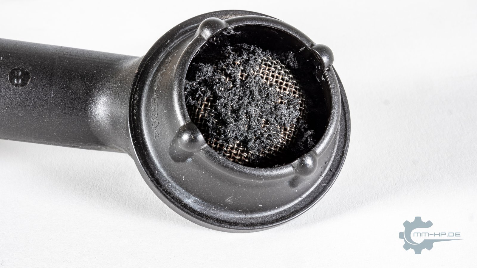 Oil pump pickup with the strainer thickly covered in black fibrous debris